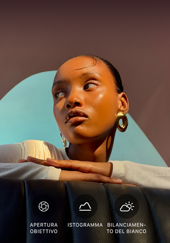 Primo piano di una persona ben illuminata su uno sfondo colorato, a mostrare l’interfaccia dei controlli professionali del sistema di fotocamere Pro: apertura dell’obiettivo, istogramma e bilanciamento del bianco